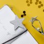 Flat lay of a notebook with motivational text, trophy, and star confetti on a yellow background.